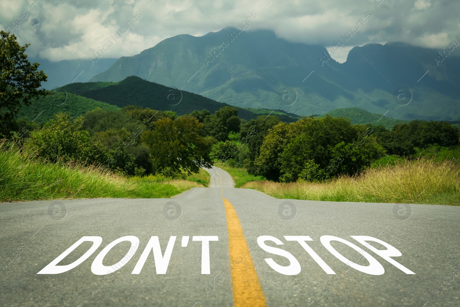 Image of Motivational phrase. Words Don't Stop written on empty road leading to mountains