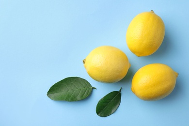 Photo of Ripe fresh lemon fruits and leaves on light blue background, flat lay. Space for text
