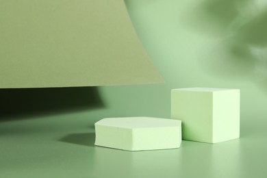 Photo of Presentation of product. Podiums, paper and shadows on green background. Space for text