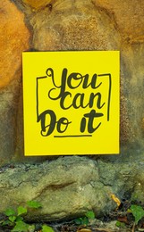 Photo of Yellow paper note with phrase You Can Do It on stone background