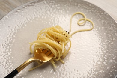 Photo of Heart made with cooked spaghetti and fork on plate, closeup