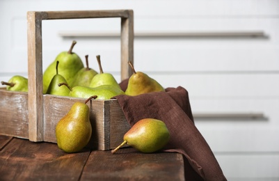 Basket with ripe pears on wooden table