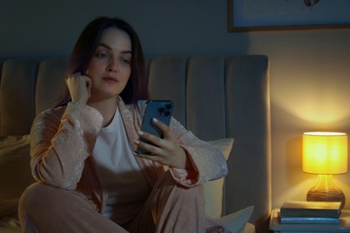 Woman using smartphone in bedroom at night. Internet addiction