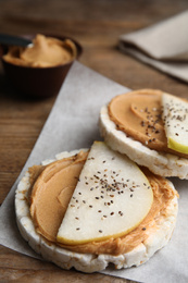 Photo of Puffed rice cakes with peanut butter and pear on wooden table
