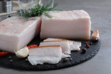 Photo of Pork fatback with spices served on grey table, closeup