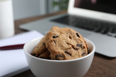 Photo of Bowl with chocolate chip cookies on table in office, closeup