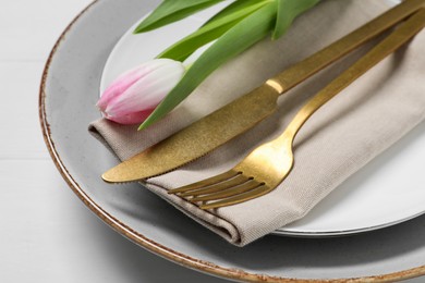 Stylish table setting with cutlery and tulip on white wooden background