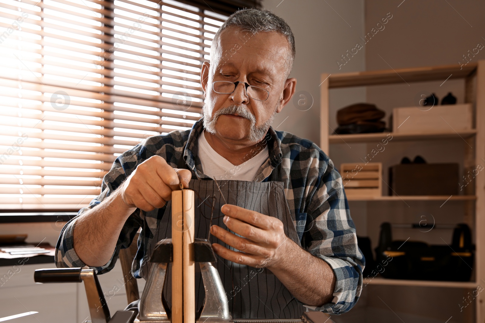 Photo of Man sewing piece of leather in workshop