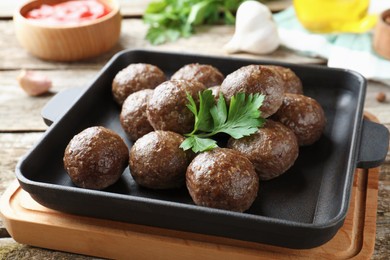 Photo of Tasty cooked meatballs with parsley on wooden table, closeup