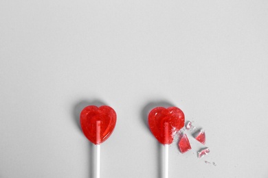 Whole and broken heart shaped lollipops on white background, top view. Space for text