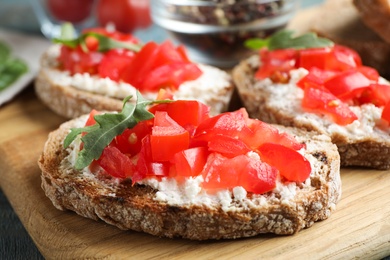 Photo of Wooden board with delicious tomato bruschettas on table, closeup