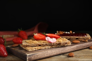 Fresh rye crispbreads with different toppings on wooden table. Space for text