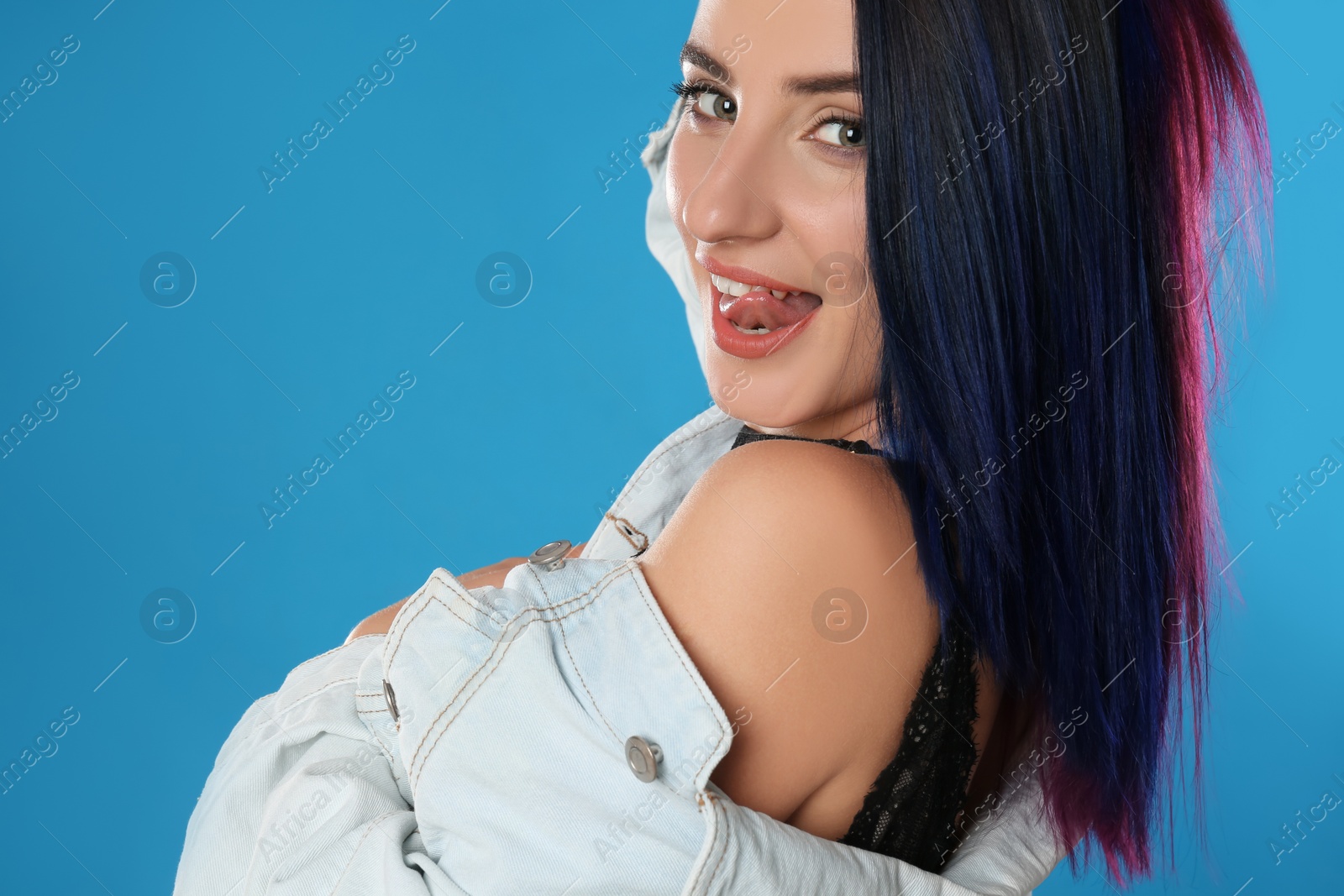 Photo of Young woman with bright dyed hair on blue background, closeup