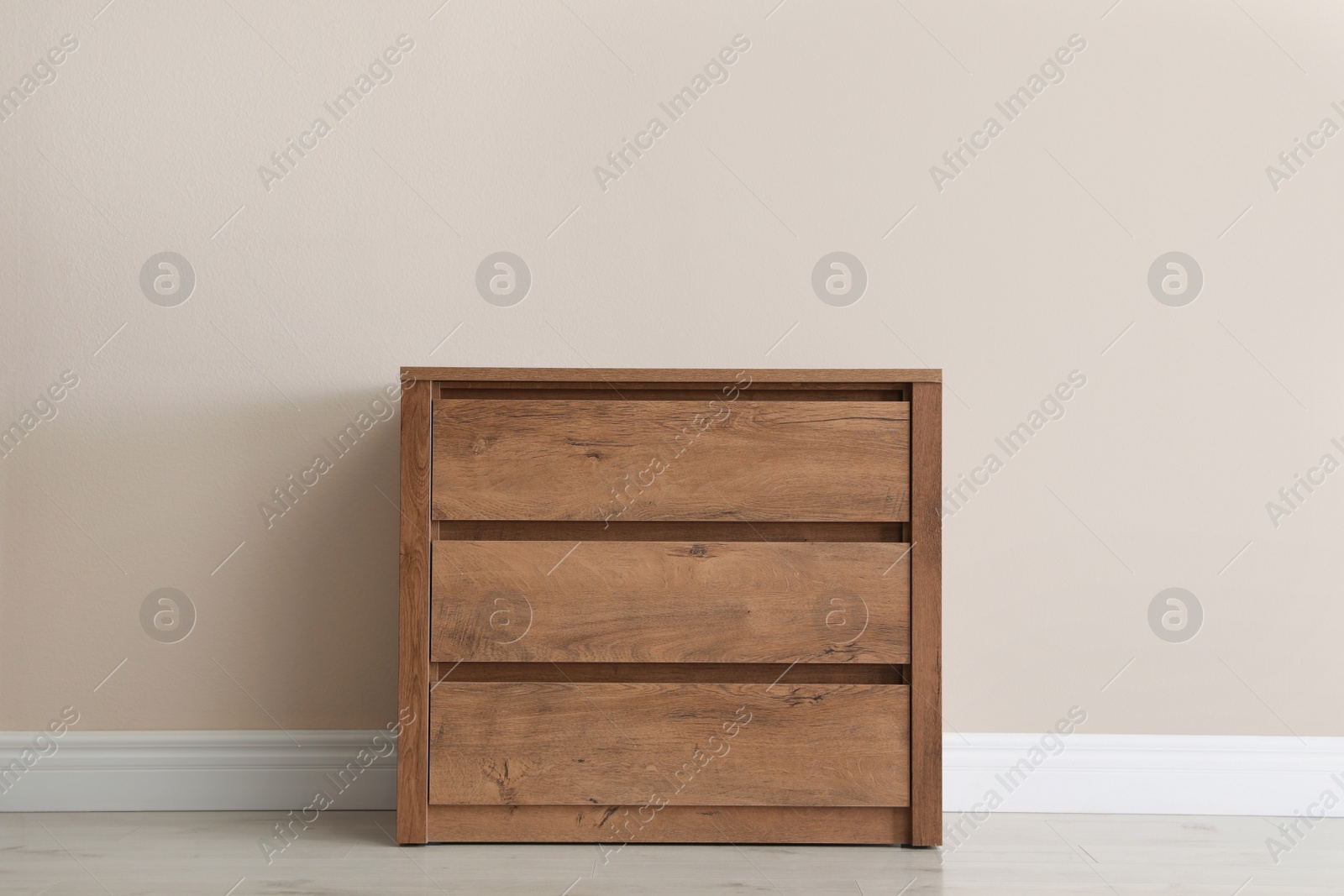 Photo of Wooden chest of drawers near beige wall