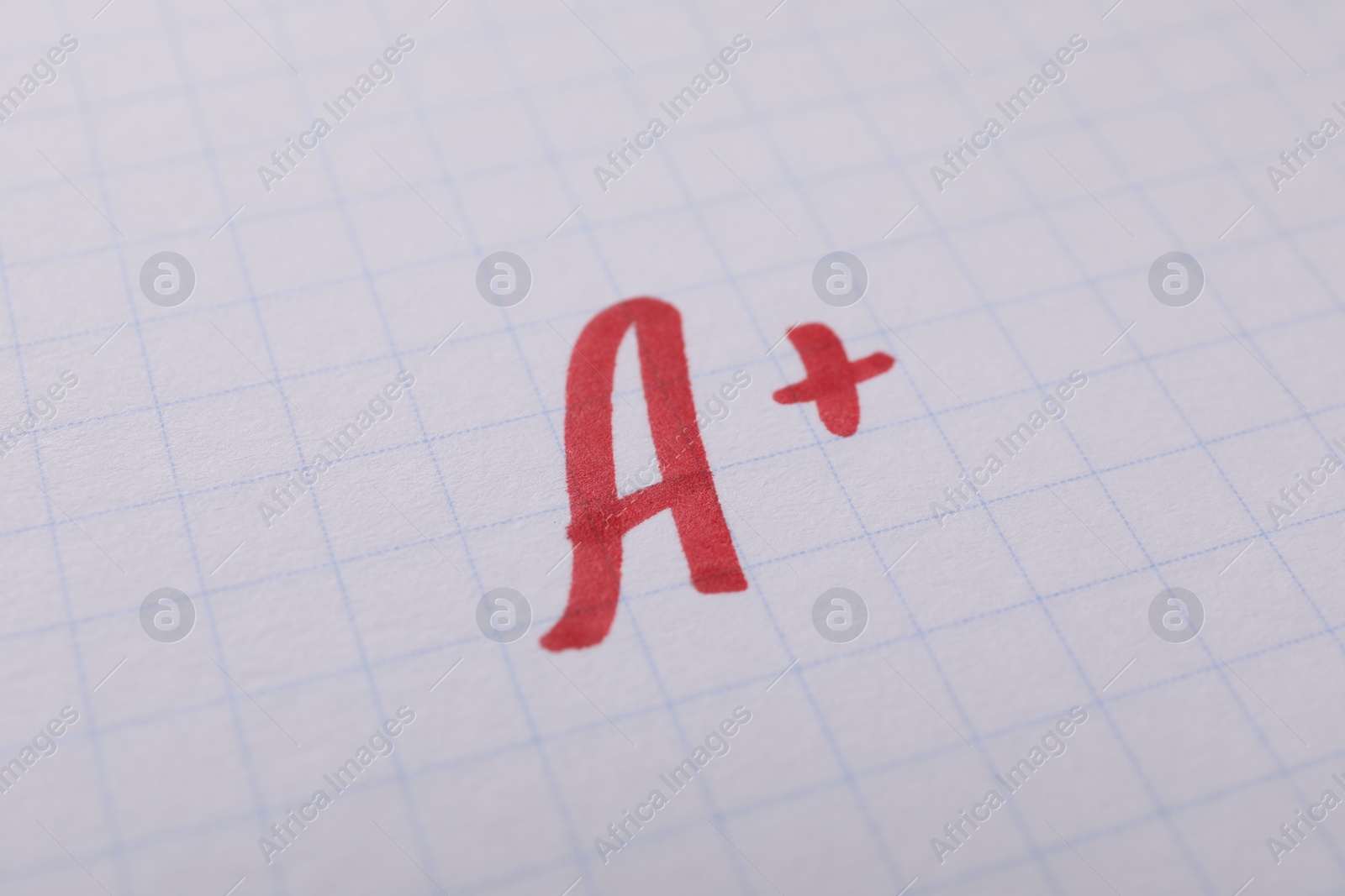 Photo of School grade. Red letter A with plus symbol on notebook paper, closeup