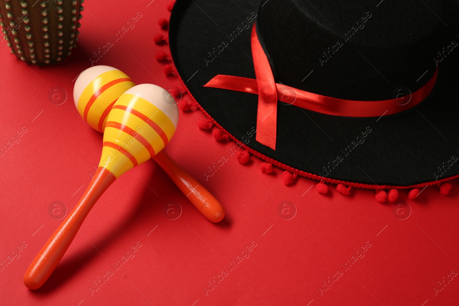 Photo of Mexican sombrero hat and maracas on red background