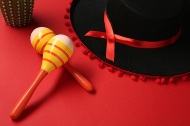 Mexican sombrero hat and maracas on red background
