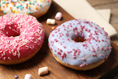 Photo of Yummy donuts with sprinkles on board, closeup