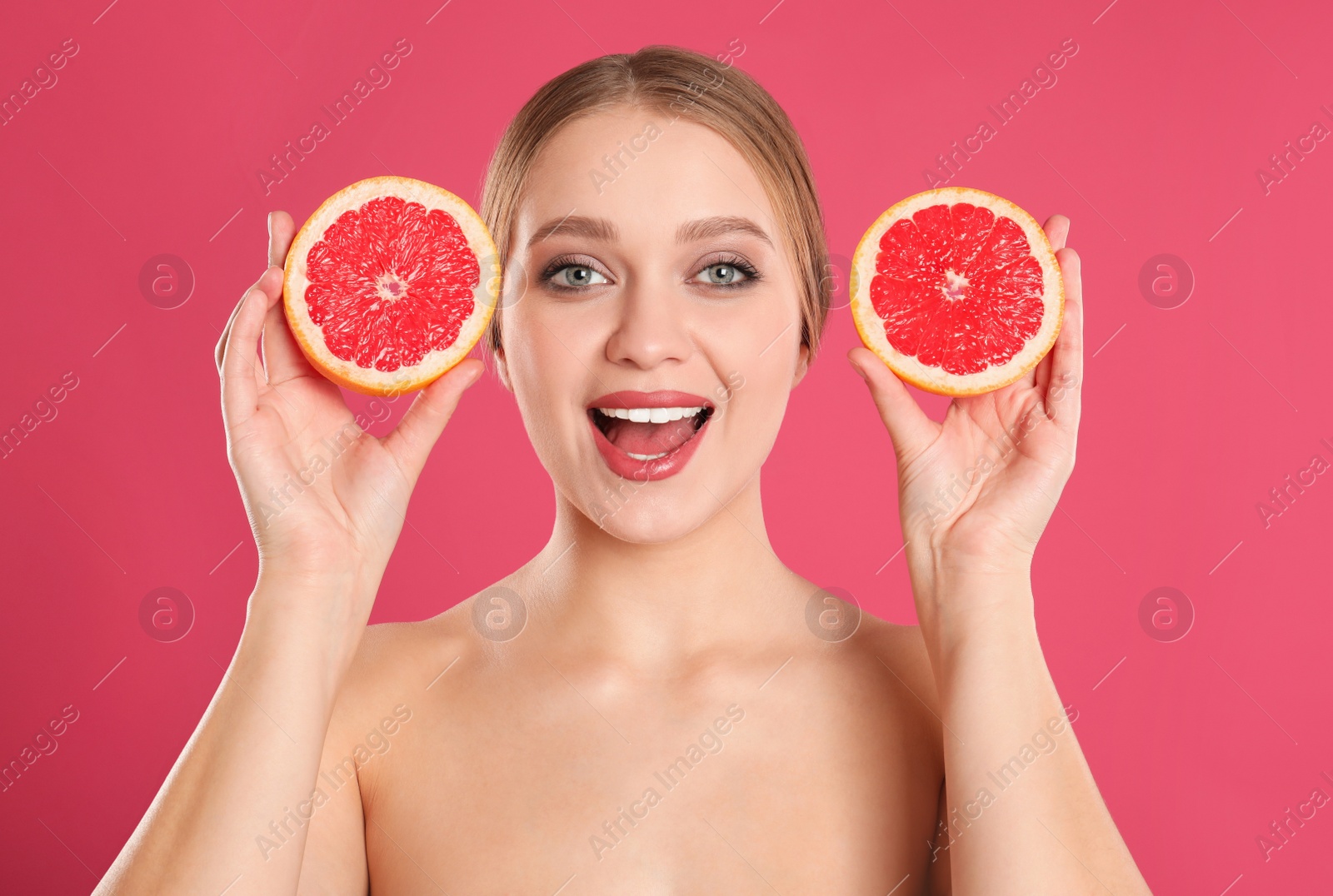 Photo of Young woman with cut grapefruit on pink background. Vitamin rich food