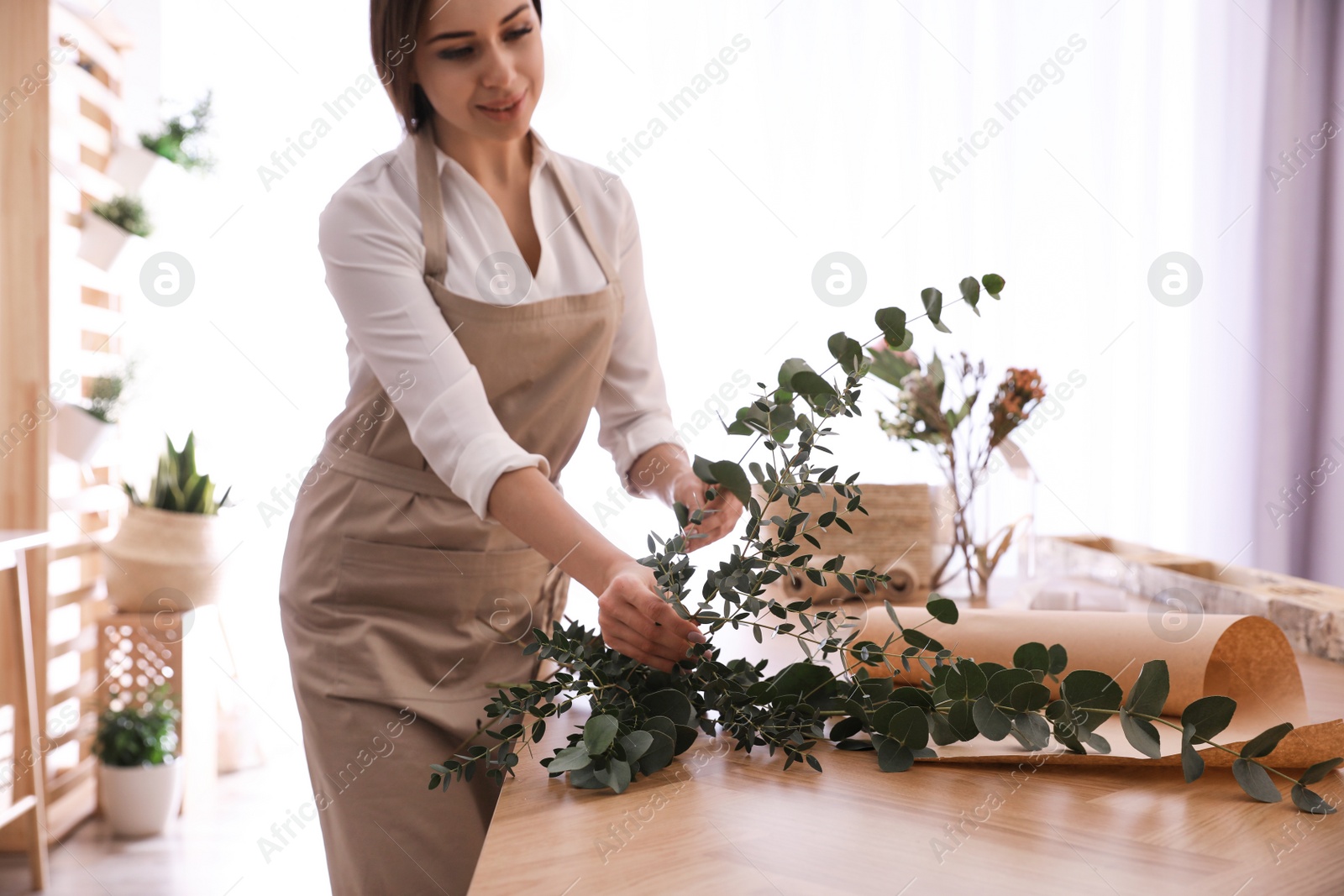 Photo of Florist making beautiful bouquet at table in workshop