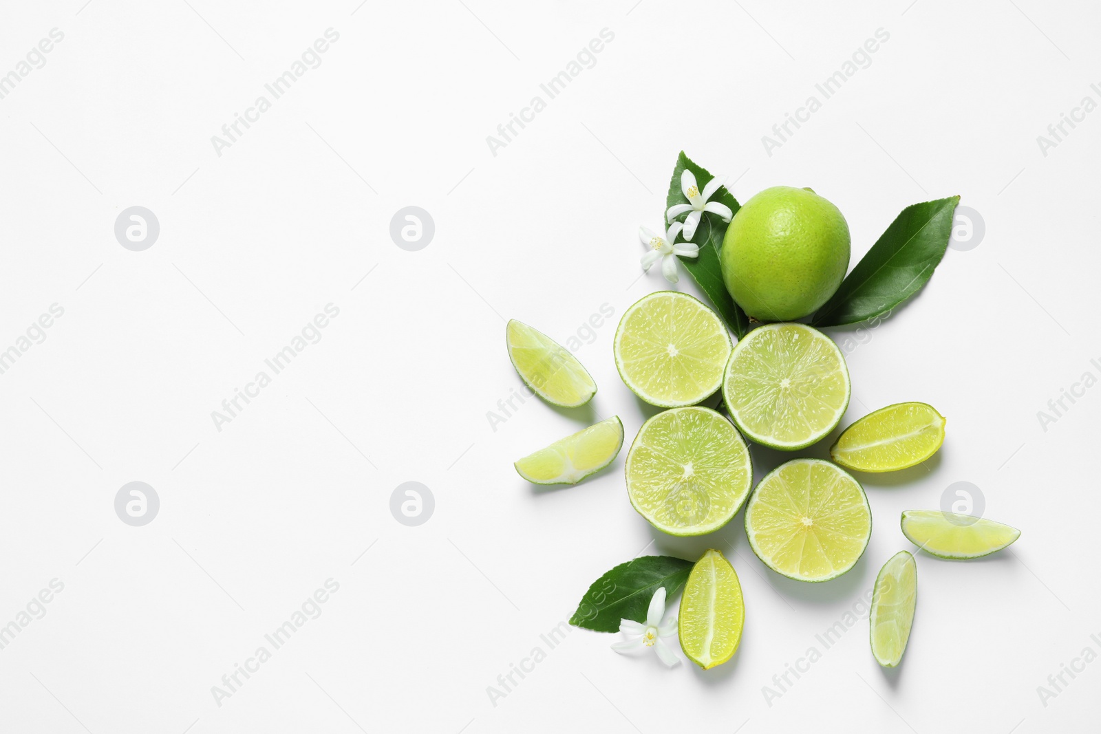 Photo of Limes, flowers and leaves on white background, top view. Citrus fruits