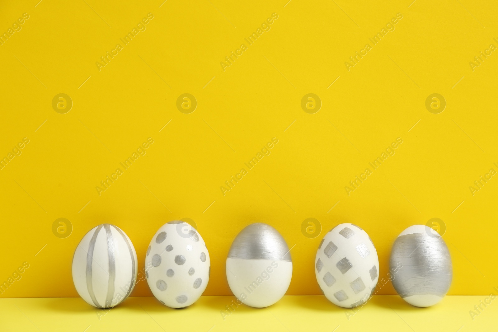 Photo of Painted Easter eggs on table against color background. Space for text