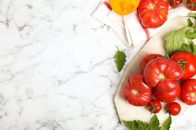 Photo of Flat lay composition with different ripe tomatoes and leaves on white marble table. Space for text