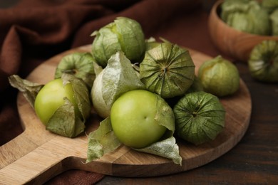 Photo of Fresh green tomatillos with husk on wooden table, closeup