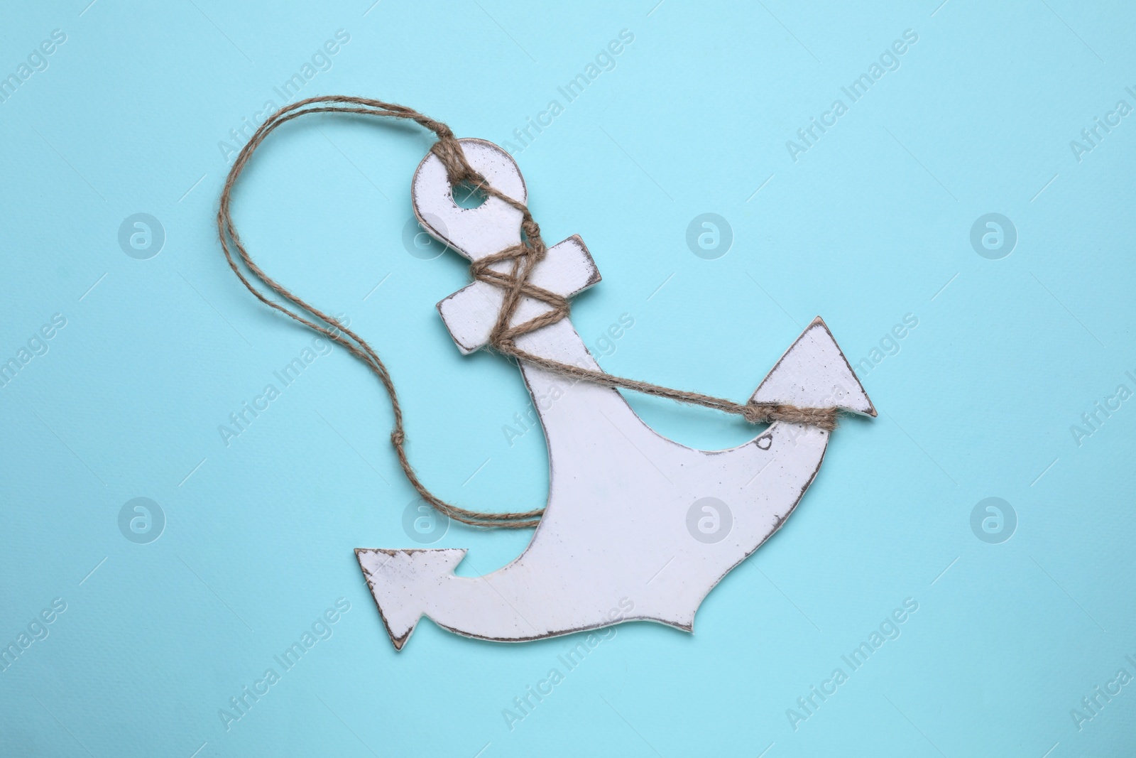 Photo of White wooden anchor figure on light blue background, top view