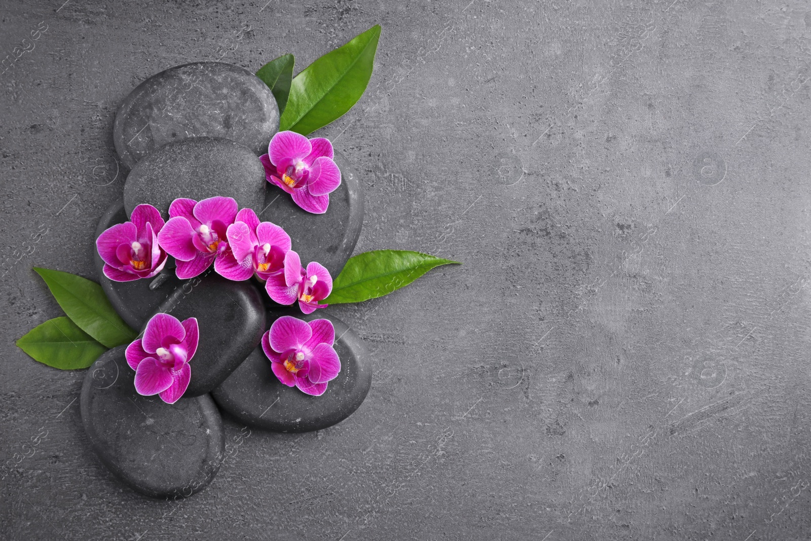 Photo of Flat lay composition with spa stones and orchid flowers on grey background. Space for text