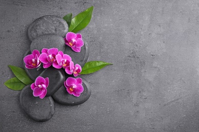 Photo of Flat lay composition with spa stones and orchid flowers on grey background. Space for text