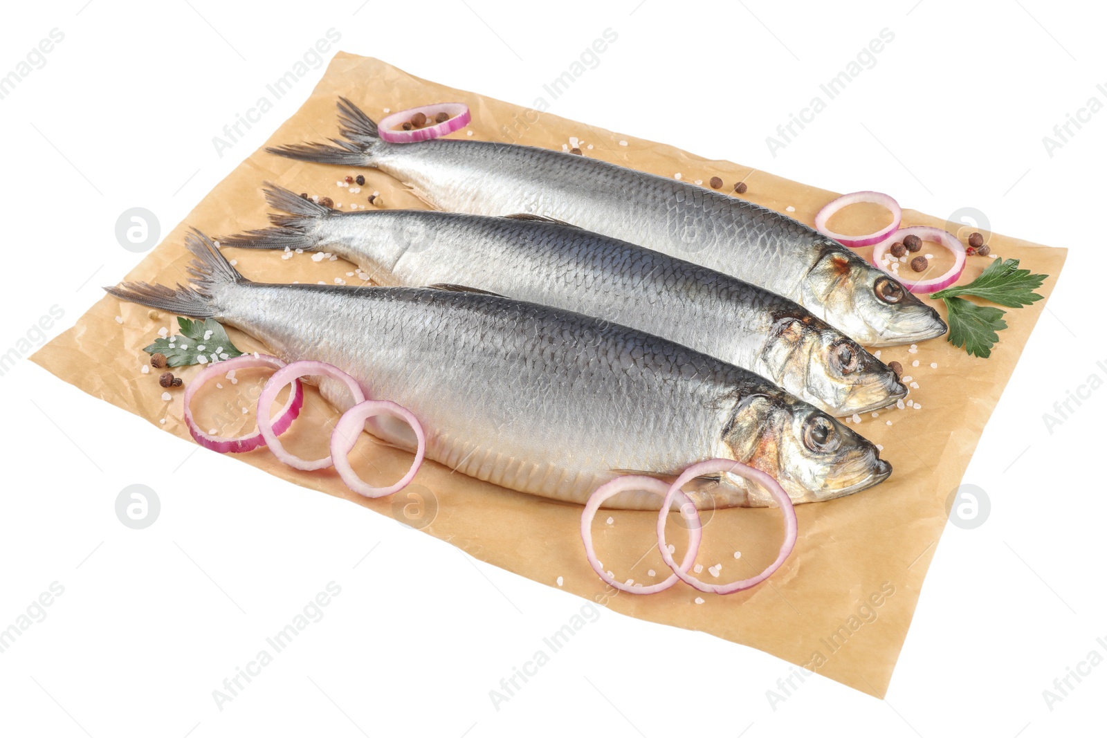 Photo of Parchment paper with salted herrings, onion rings, peppercorns and parsley isolated on white