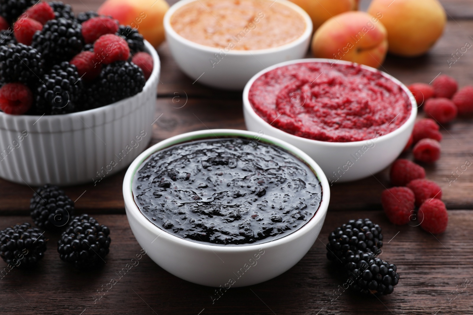 Photo of Different puree in bowls and fresh fruits on wooden table