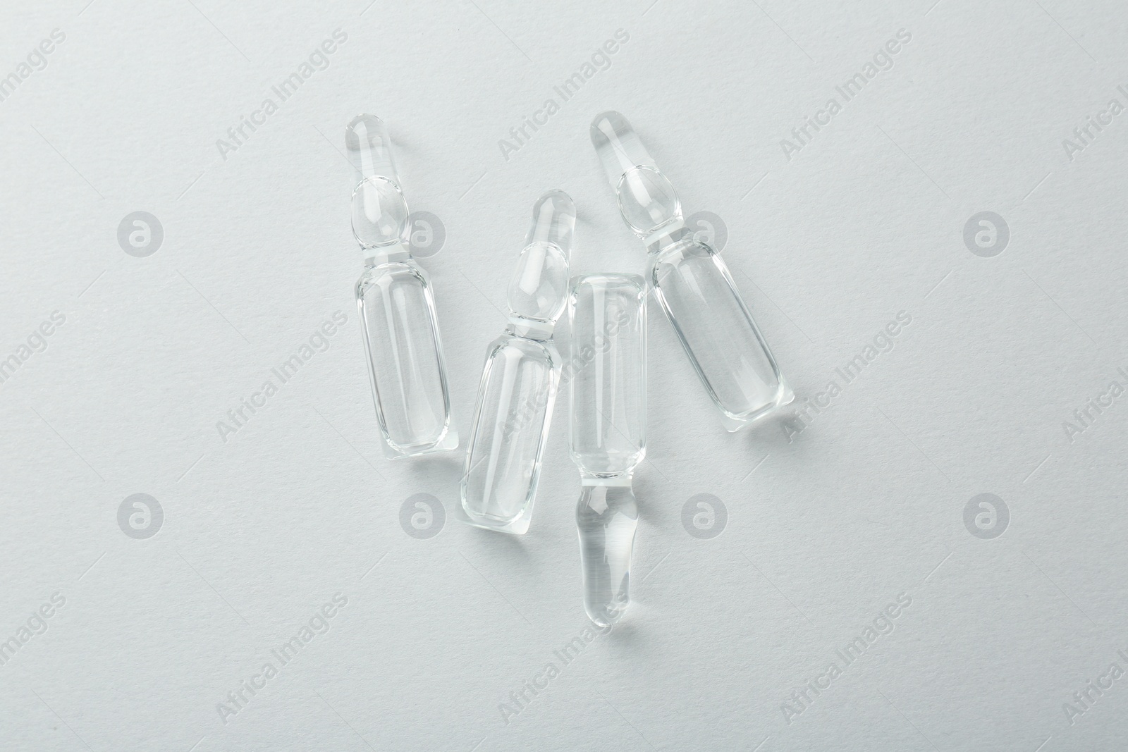 Photo of Glass ampoules with liquid on white background, top view