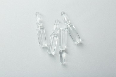 Photo of Glass ampoules with liquid on white background, top view