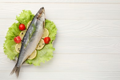 Photo of Delicious salted herring, rosemary, lettuce, tomatoes and lemon on white wooden table, top view. Space for text
