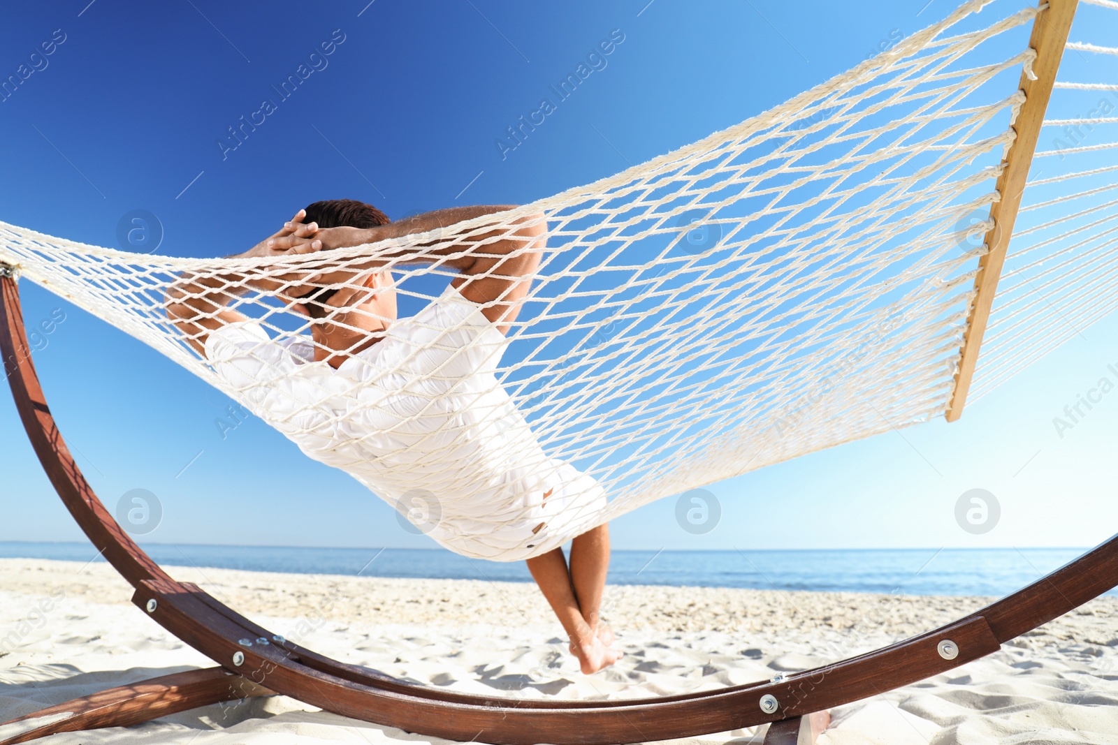 Photo of Man relaxing in hammock on beach. Summer vacation