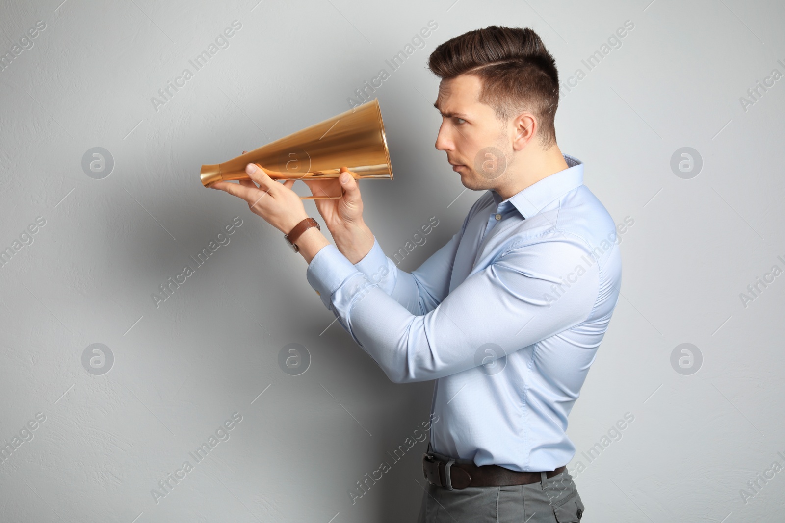 Photo of Young man with megaphone on light background