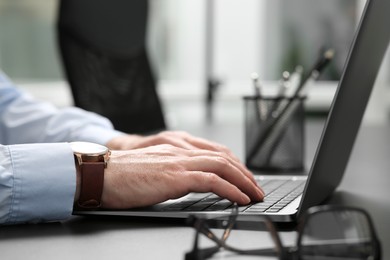 Man working on laptop at black desk in office, closeup