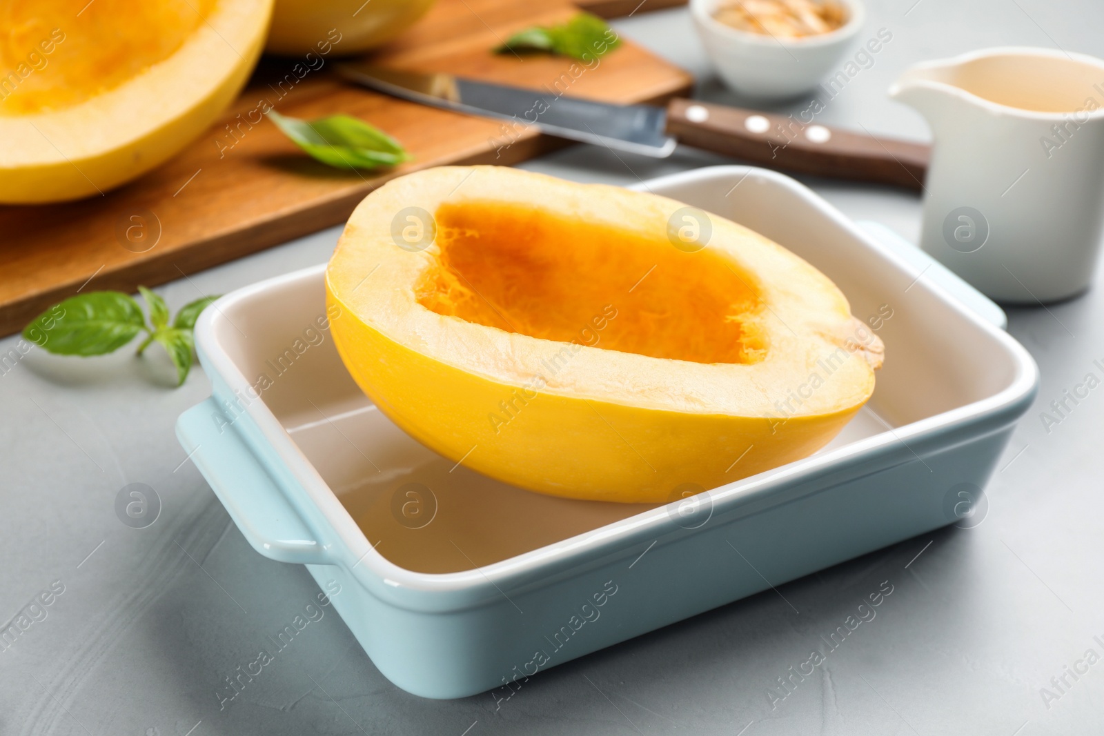 Photo of Raw spaghetti squash half in baking dish on light table