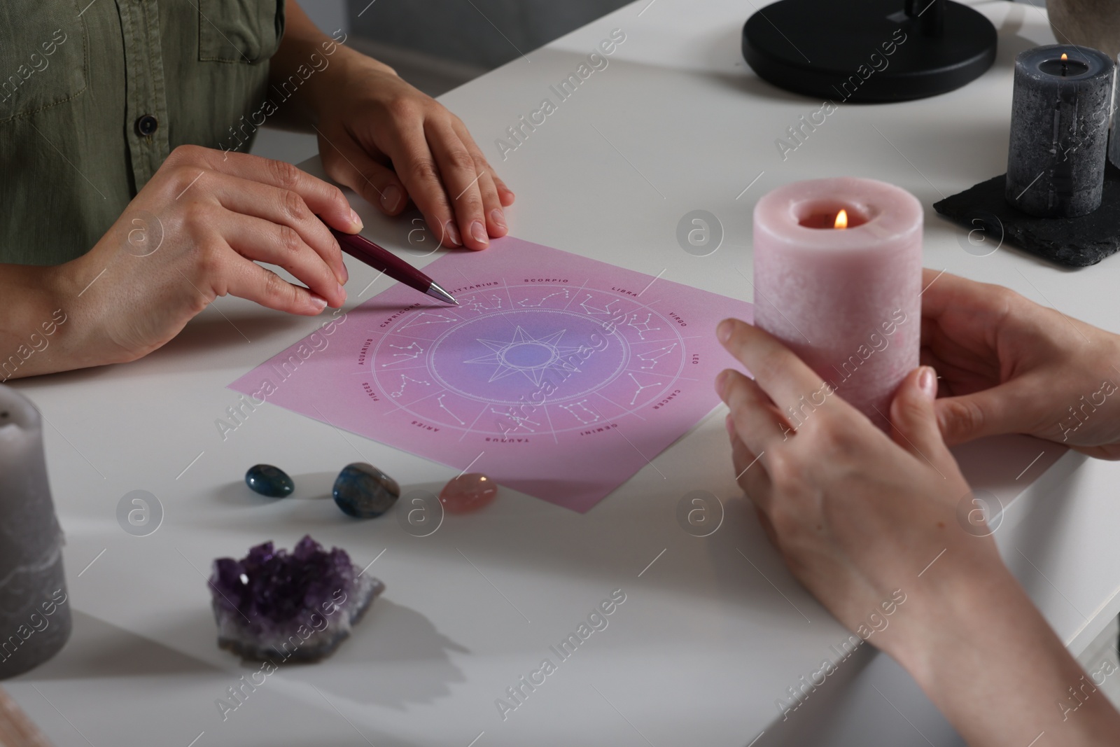 Photo of Astrologer predicting client's future with natal chart at table, closeup