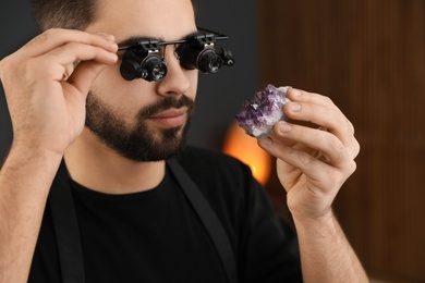 Male jeweler evaluating semi precious gemstone in workshop, closeup