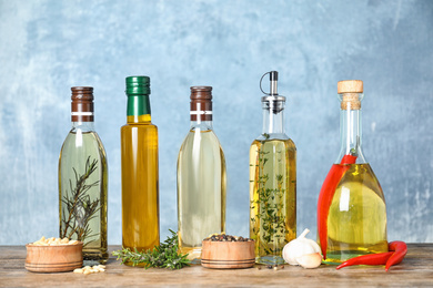 Photo of Different cooking oils in bottles on wooden table