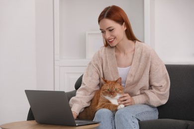 Happy woman with cat working on sofa at home