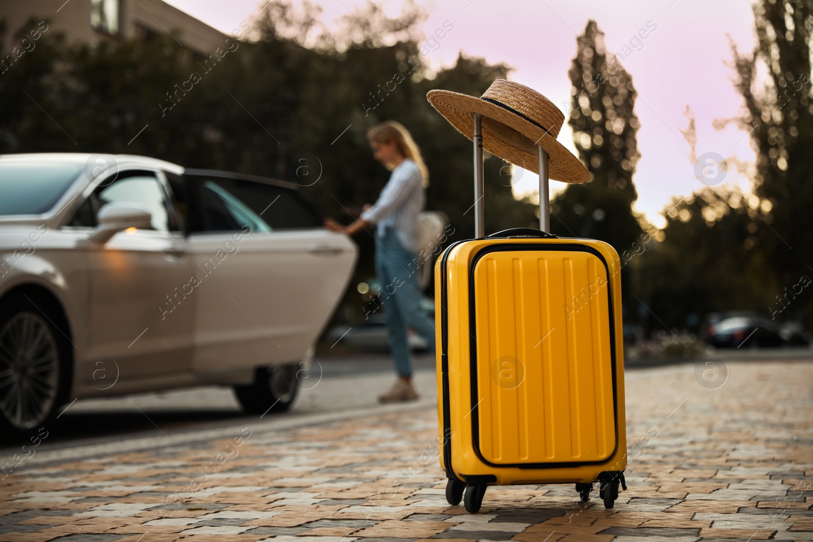 Photo of Woman near taxi outdoors, focus on suitcase