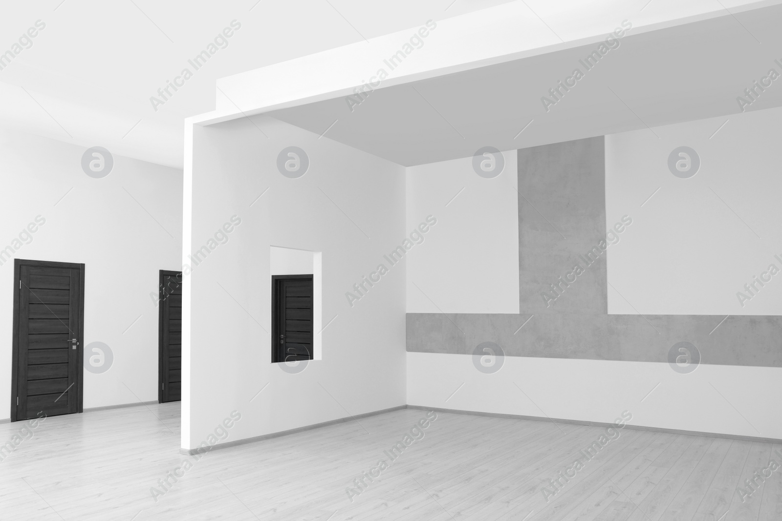 Photo of White walls, opening for fake window and wooden doors in spacious room during repair