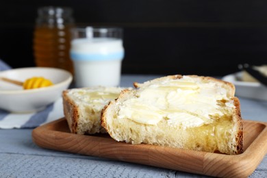 Slices of bread with butter, honey and milk on grey wooden table, closeup