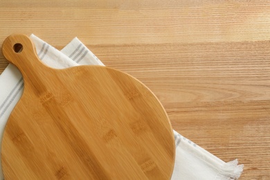 Photo of Empty wooden board and napkin on table, top view. Space for text