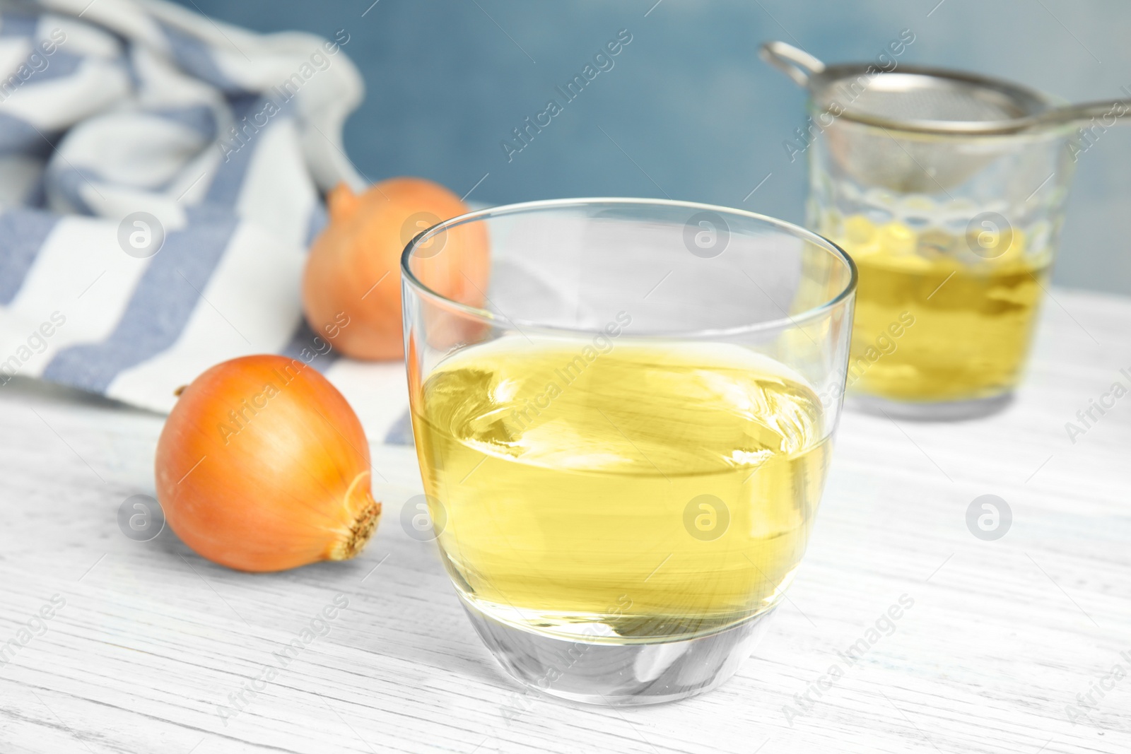 Photo of Glass of onion syrup and fresh vegetable on table