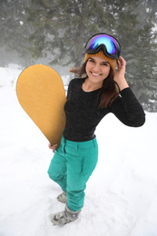 Photo of Young woman with snowboard wearing winter sport clothes outdoors